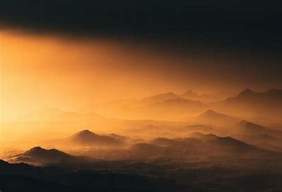 foggy mountains with sunsetting behind them